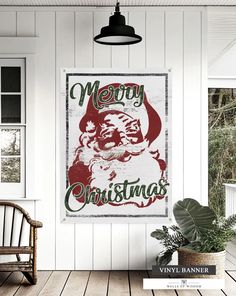 a merry christmas sign hanging on the side of a white wall next to a chair