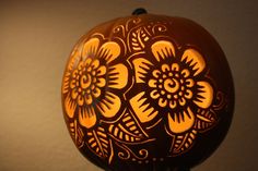 a carved pumpkin sitting on top of a table next to a light fixture with flowers painted on it