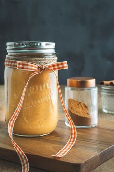 a jar filled with food sitting on top of a wooden cutting board next to two jars