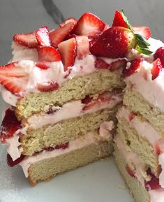 a cake with white frosting and strawberries on top is cut in half to show the layers