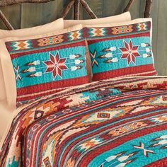 a bed covered in a colorful quilt and pillows