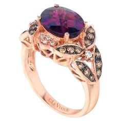 a ring with an oval shaped purple stone surrounded by brown and white diamonds on top