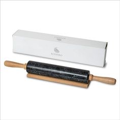 a black rolling stone with wooden handle next to a white box