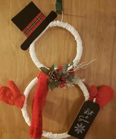 a snowman wreath and hat hanging on a table with a chalkboard sign attached to it