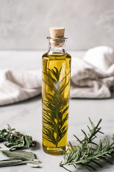 a bottle filled with olive oil next to some herbs