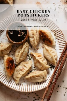 a white plate topped with dumplings covered in sauce next to two chopsticks