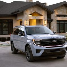 a white suv is parked in front of a large house with two cars on the driveway