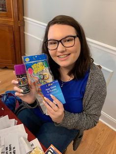 a woman sitting on the floor holding up a box with some kind of candy in it