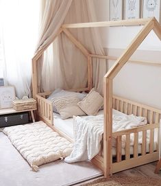 a wooden bed with a canopy over it and pillows on the floor next to it