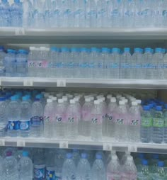 several rows of bottled water on shelves in a grocery store, one is blue and the other is pink