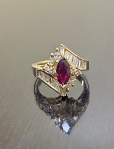 DeKara Designs Classic A ring my father Setrag Karadolian designed and made himself over 30 years that is back in fashion today! Beautiful Art Deco Ruby and Diamond Ring Handmade By A True Artist. Metal- 14K Yellow Gold, .583 Stones- 1 Natural Marquise Shaped Ruby Red in Color 0.85 Carats, 14 Baguette Diamonds, 4 Marquise Diamonds, 4 Round Diamonds, G-H Color VS1-VS2 Clarity 1.15 Carats. Handmade 14K Yellow Gold Marquise Ruby Baguette, Marquise, and Round Diamond Engagement Ring. This ring featu Luxury Marquise Cut Ruby Ring Fine Jewelry, Diamond Ring With Ruby Side Stones, Ruby Marquise Engagement Ring, Art Deco Ruby Engagement Ring, Art Deco Gemstone Ring, Ruby Engagement Ring Art Deco, Ruby Art Deco Ring, Ruby Marquise Ring, Ruby Wedding Ring Vintage