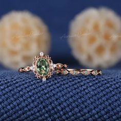 a close up view of a ring with an oval green stone in the center and diamond accents