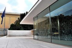 a building with glass walls and flags on the outside