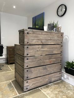 a wooden dresser sitting on top of a tiled floor next to a wall with a clock above it