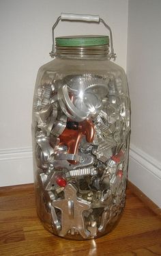 a glass jar filled with lots of silverware sitting on top of a wooden floor