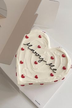 a heart shaped cake sitting on top of a white box with the word happy birthday written on it