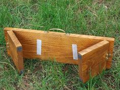 a wooden box sitting in the grass with two silver tags on it's sides