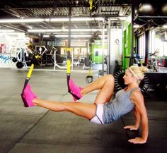 a woman doing exercises on a hammock in a gym with her legs spread out