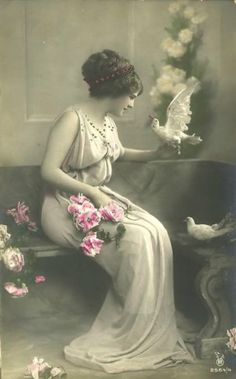 an old fashion photo of a woman with flowers and a bird in her hand, sitting on a couch