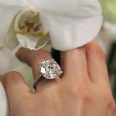 a close up of a person's hand with a diamond ring on their finger