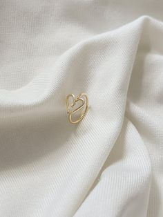 a close up view of a white fabric with a small gold heart pin on it