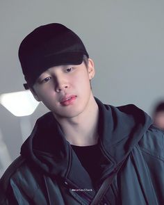 a young man wearing a black hat and jacket looking at the camera with an intense look on his face