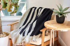 a black and white striped blanket sitting on top of a chair next to a potted plant