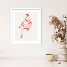 a white table with a vase, plant and framed photograph on the wall next to it