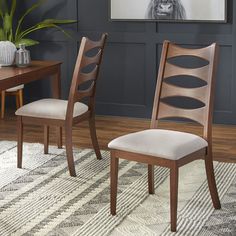 two wooden chairs sitting on top of a rug