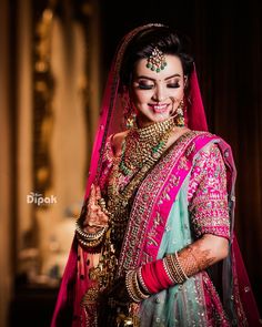 a woman in a pink and green bridal outfit with jewelry on her head, smiling