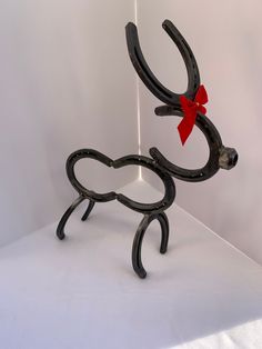 a metal sculpture with a red bow on it's head and legs, sitting on a white surface