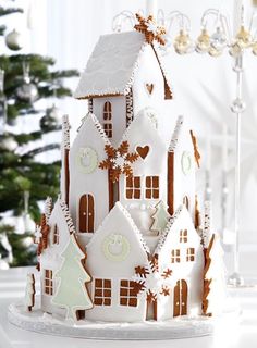 a christmas cake is decorated with gingerbread and white icing on a table in front of a christmas tree