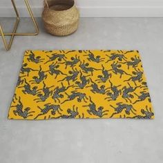 a yellow and black pattern rug on the floor next to a basket with a plant in it