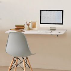 a desk with a computer on top of it next to a stack of books and a plant