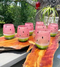 a group of pink glasses sitting on top of a wooden table next to a potted plant