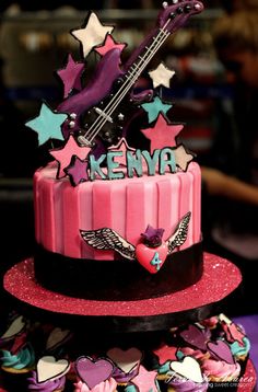 a pink and black cake with stars on it's sides, decorated with music instruments