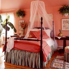 a bedroom with pink walls and white bedding, decorated with potted palm trees