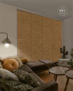 a living room with couches, coffee table and large window blinds in the corner