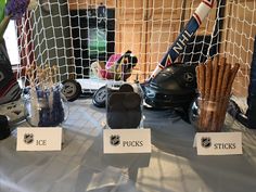 the table is set up with hockey equipment and puckers'sticks for sale in front of an ice goal