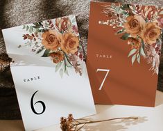 the table numbers are placed next to each other on top of cards with orange flowers