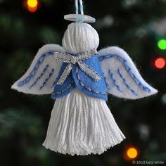 a white and blue angel ornament hanging from a christmas tree