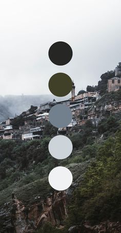 a group of circles hanging from the side of a hill next to a town on top of a mountain