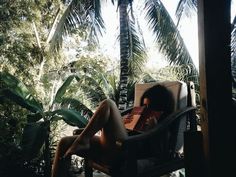 a woman is sitting in a chair with her legs spread out and reading a book