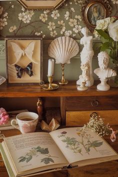 an open book sitting on top of a wooden table next to vases and flowers