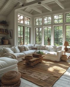 a living room filled with lots of white furniture and large windows above the couches