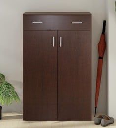 a brown cabinet sitting next to a clock on a wall with a plant in front of it