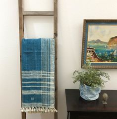 a ladder leaning against a wall next to a potted plant and painting on the wall