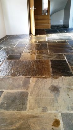 a stone floor in an empty room with stairs leading up to the door and landing area