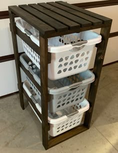 three white laundry baskets stacked on top of each other in front of a wooden shelf