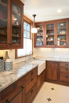 a large kitchen with wooden cabinets and marble counter tops, along with black and white tile flooring